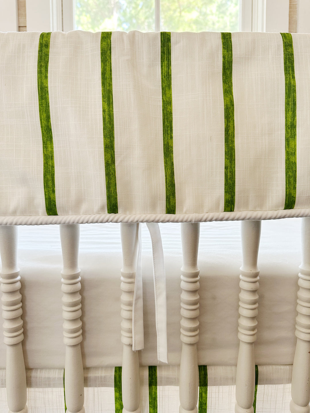 Close view of the brushed green stripes, the white cording along the bottom edge and one slim white tie