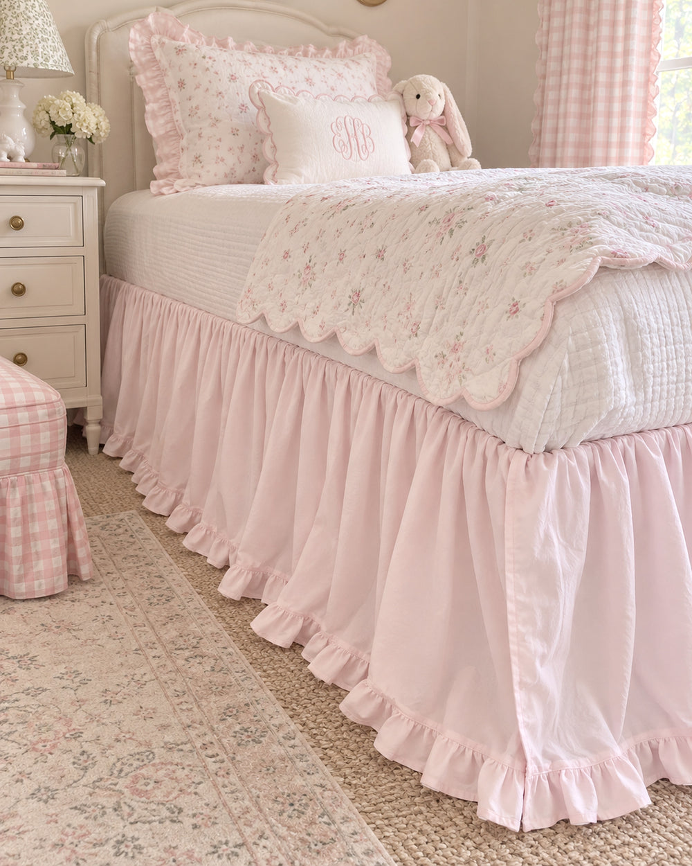 Corner of a twin bed showing the full drop and split corner of a baby pink ruffled cotton bed skirt - High Cotton Textile