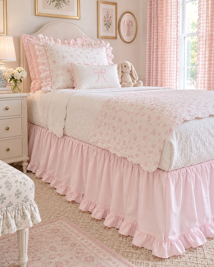 Twin bed dressed with a baby pink ruffled bed skirt, floral quilt and pink gingham curtains - High Cotton Textile