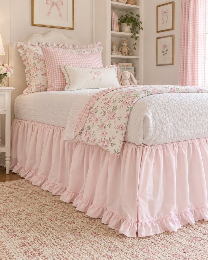 Baby pink twin bed skirt styled with a rose print quilt and gingham shams in a big kid bedroom - High Cotton Textile
