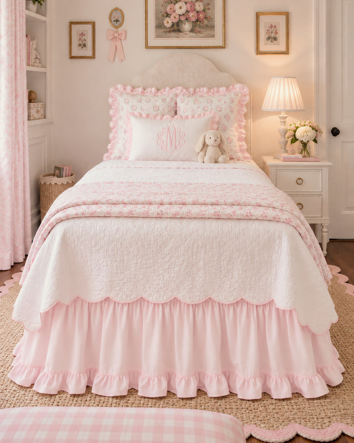Wide view of a girl's bedroom with a baby pink ruffled twin bed skirt and framed floral prints - High Cotton Textile