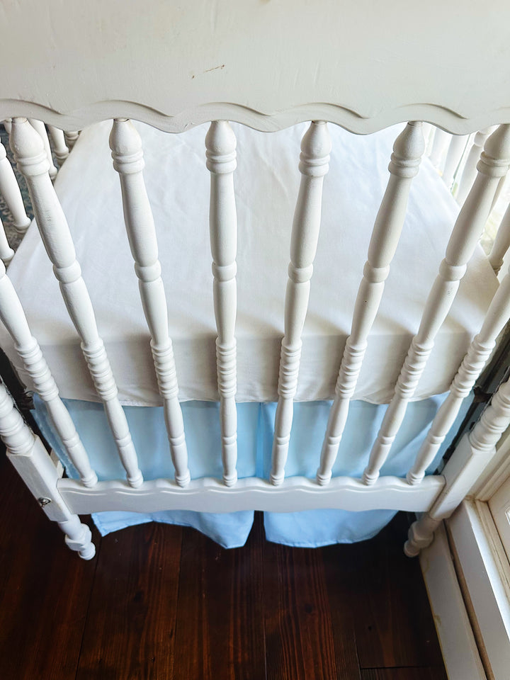 Looking down over the scalloped footboard at a white fitted sheet and the heirloom blue skirt hanging below the mattress - High Cotton Textile