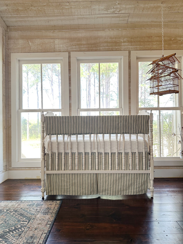 The green ticking set in a pine-paneled room with three windows and a hanging birdcage