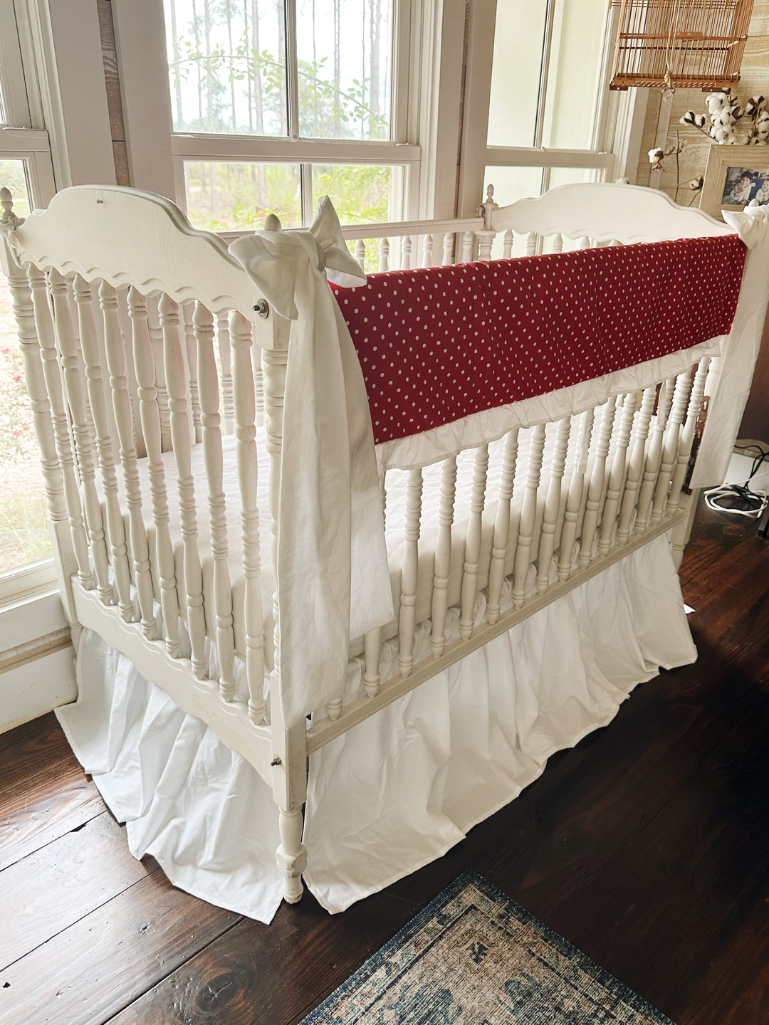 Corner view of the red polka dot rail cover with a large white bow tied to the near post