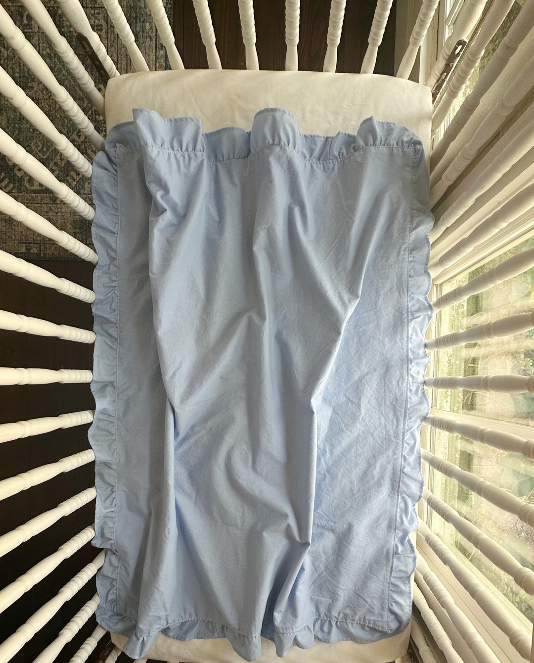 Baby blue ruffled crib blanket opened inside a crib with the ruffle framing all four sides - High Cotton Textile