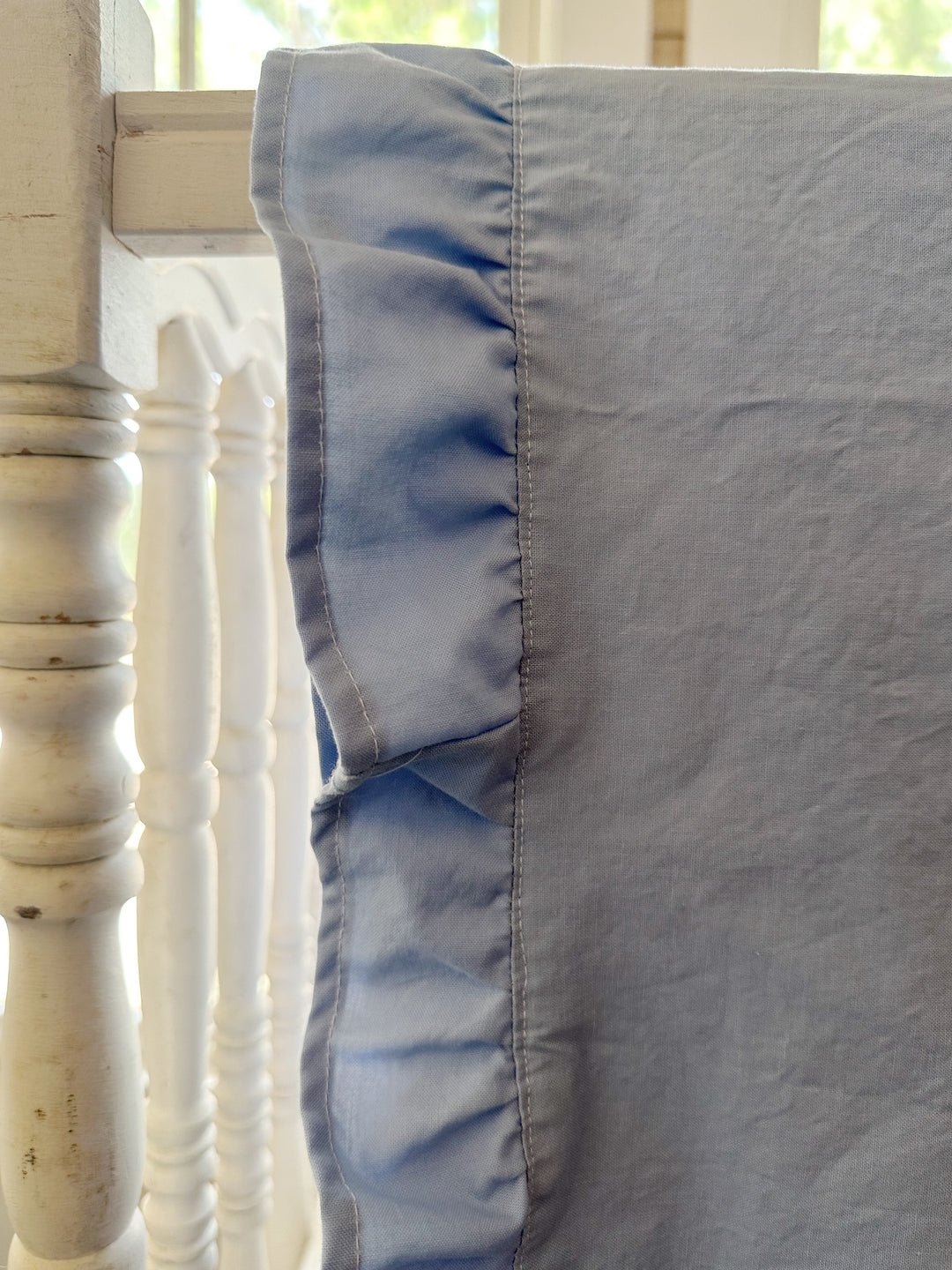 Close up of the gathered baby blue ruffle and topstitched edge on a washed cotton crib blanket - High Cotton Textile