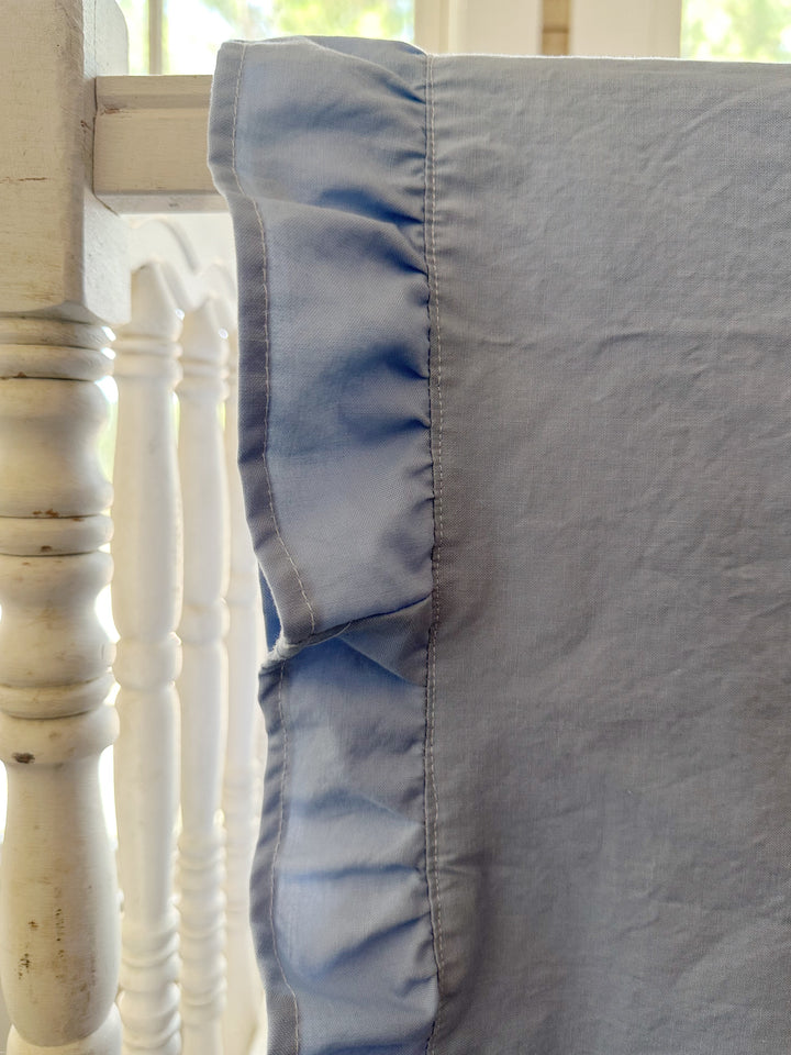 Close up of the gathered baby blue ruffle and topstitched edge on a washed cotton crib blanket - High Cotton Textile