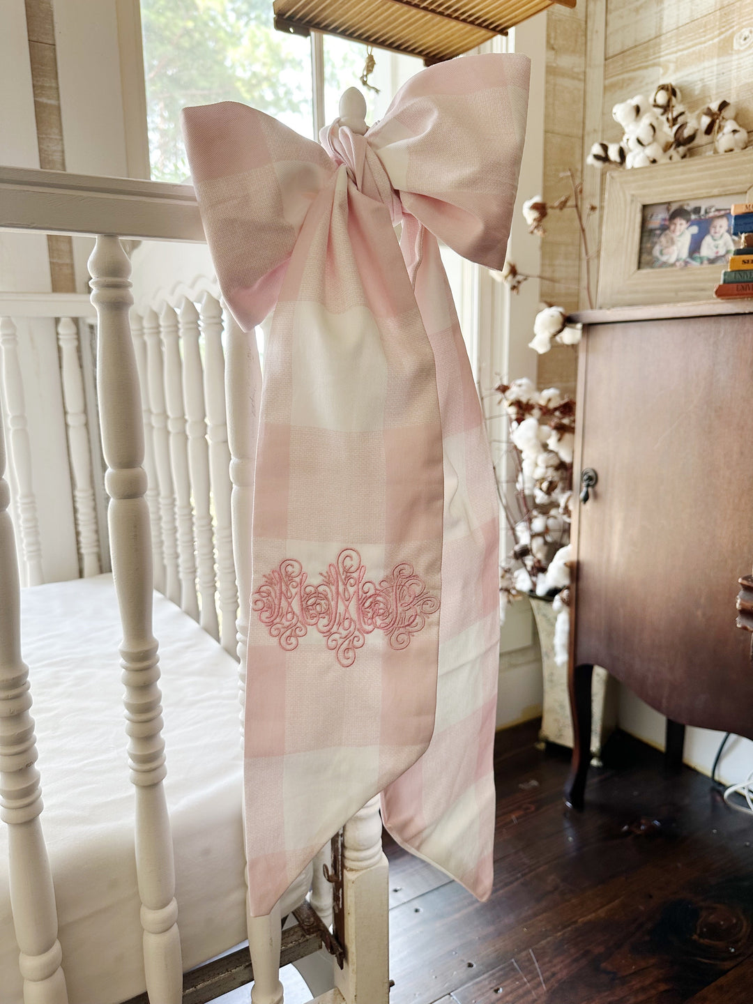 The monogrammed bow hanging beside a wooden armoire in a bright nursery corner