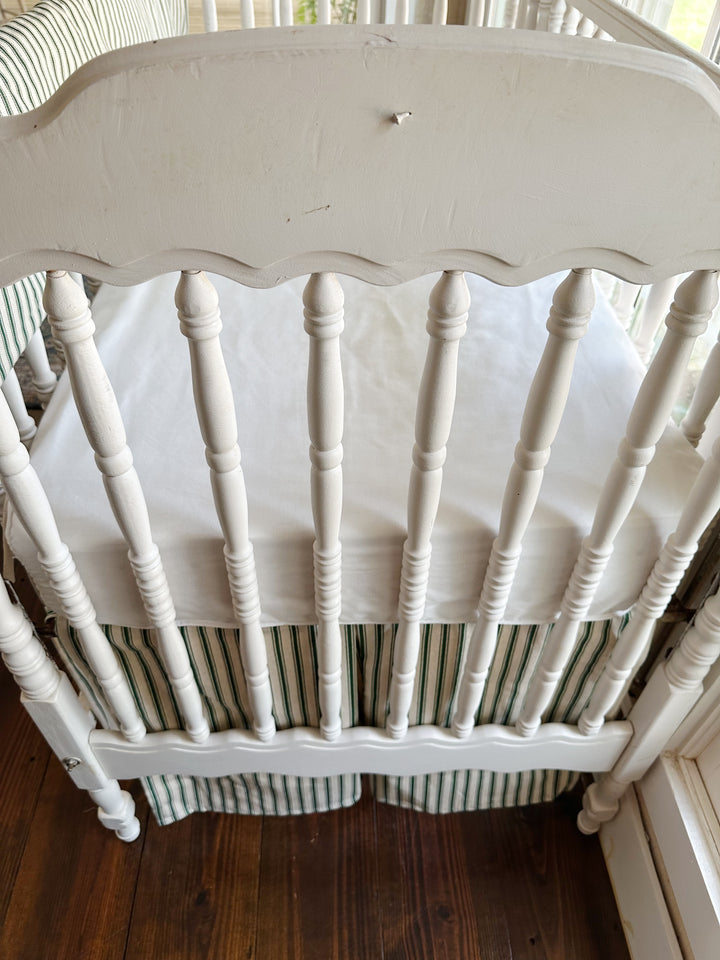 The scalloped end panel above the pleated green ticking skirt and a plain white sheet