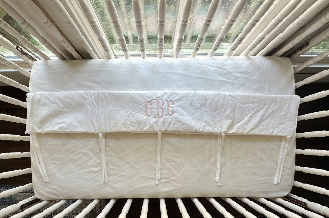 Overhead view of the monogrammed white cover showing the row of narrow cotton ties