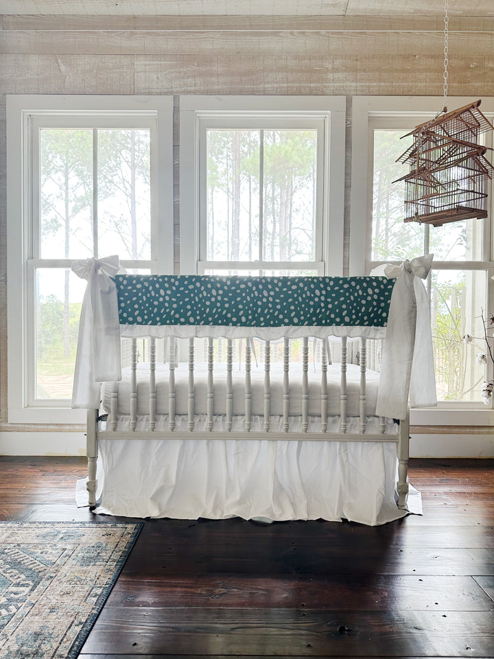 The green dot crib set in a pine-paneled nursery with three windows and a hanging birdcage
