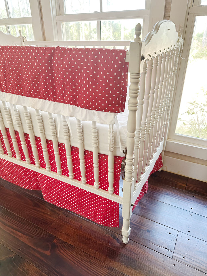 Corner view from the head of the crib, the polka dot rail cover folded over the long rail
