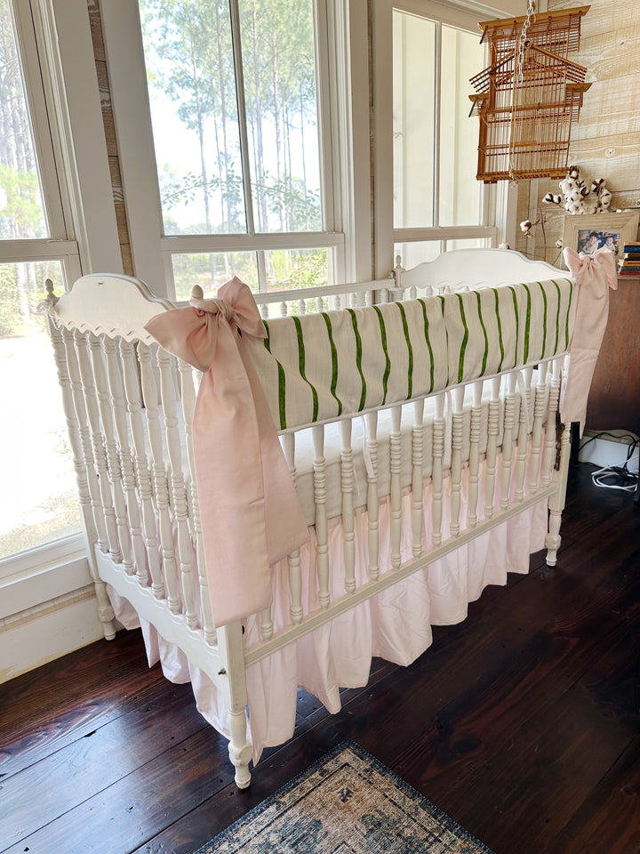Angled view of the striped rail cover above the gathered baby pink skirt, pink sash on the near post