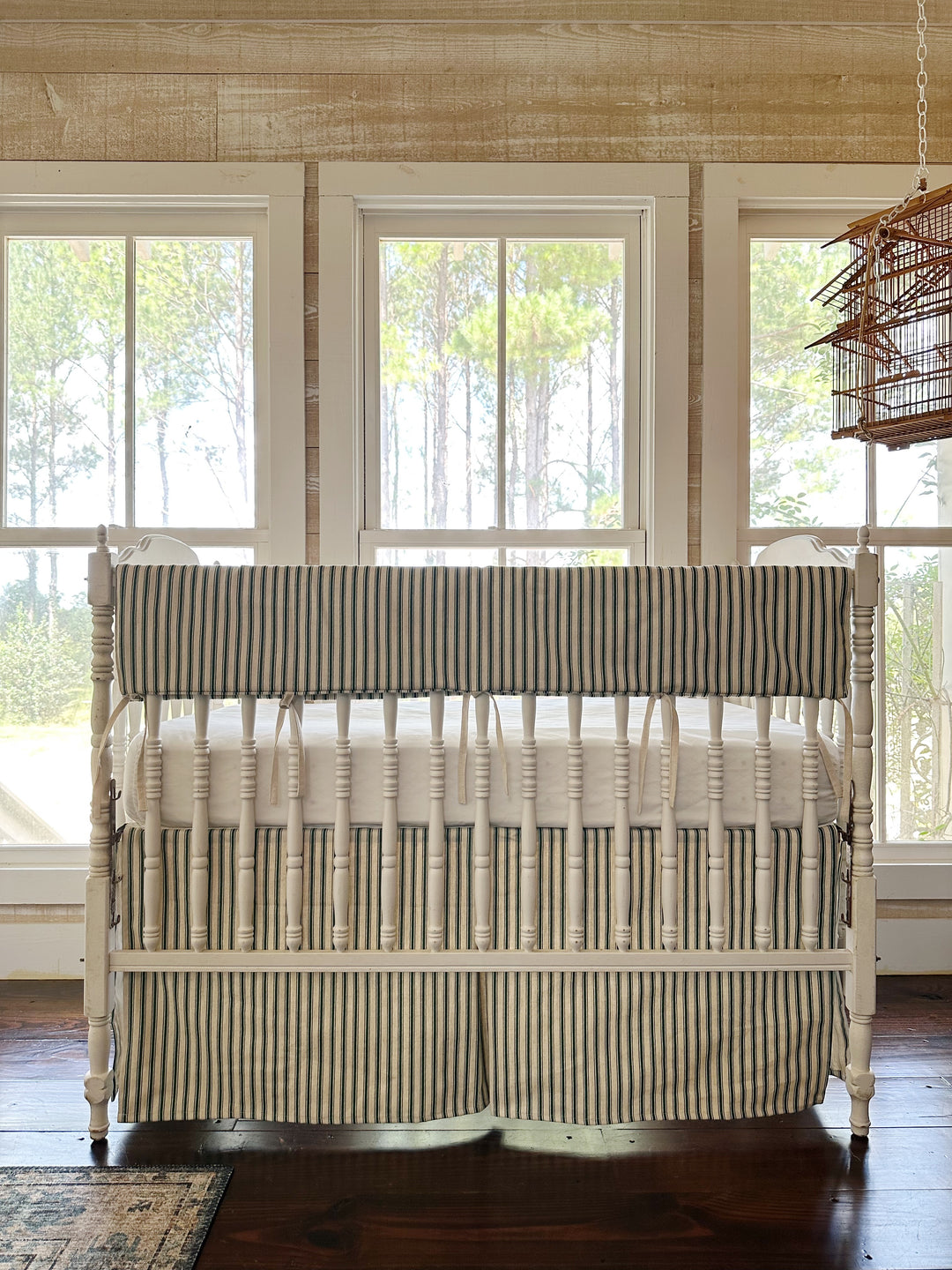 Pine green ticking simple crib rail cover with a matching tailored ticking crib skirt on a white spindle crib