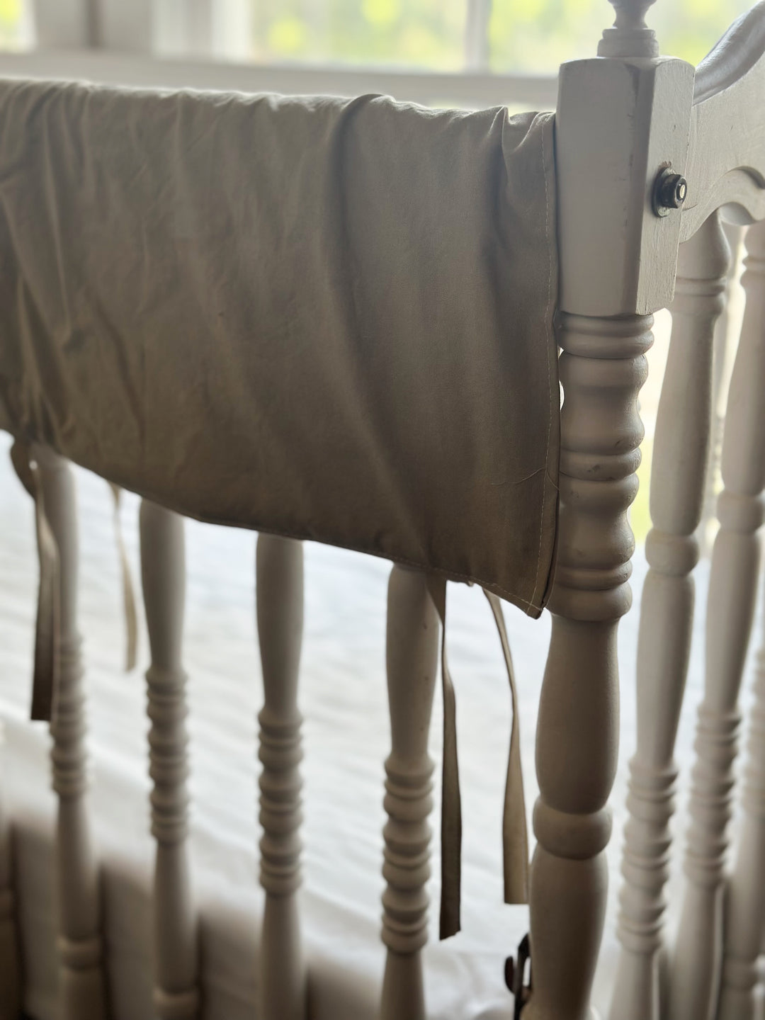 Oatmeal crib rail cover corner detail with stitched edge on white heirloom crib - High Cotton Textile
