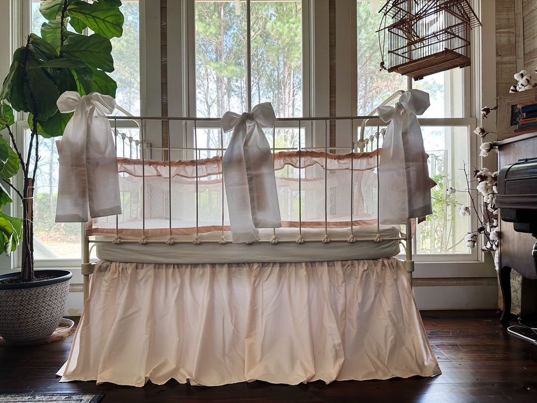 Crib with bedding set showing liners, skirt, and large bows together