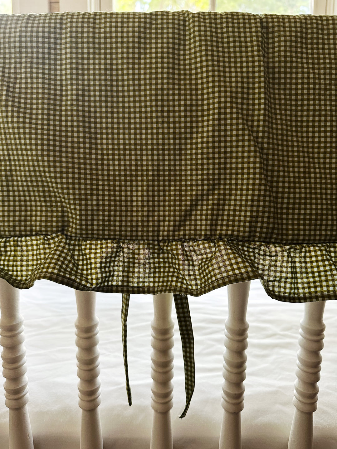 Close-up of the small green gingham check and gathered ruffle on the crib rail cover