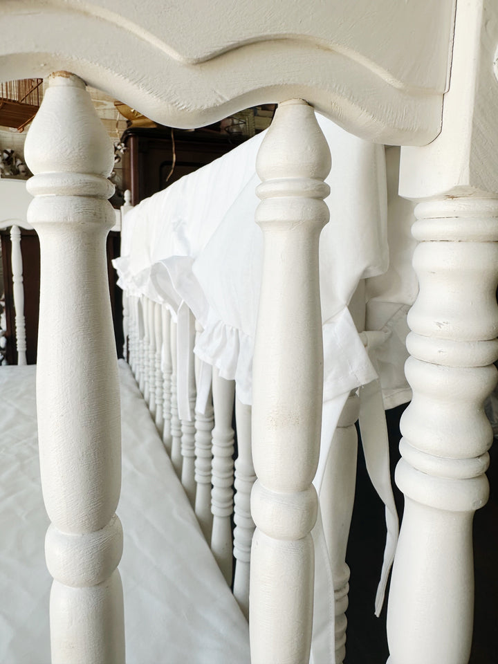 Detail of the white ruffle and cotton ties threaded between the crib spindles
