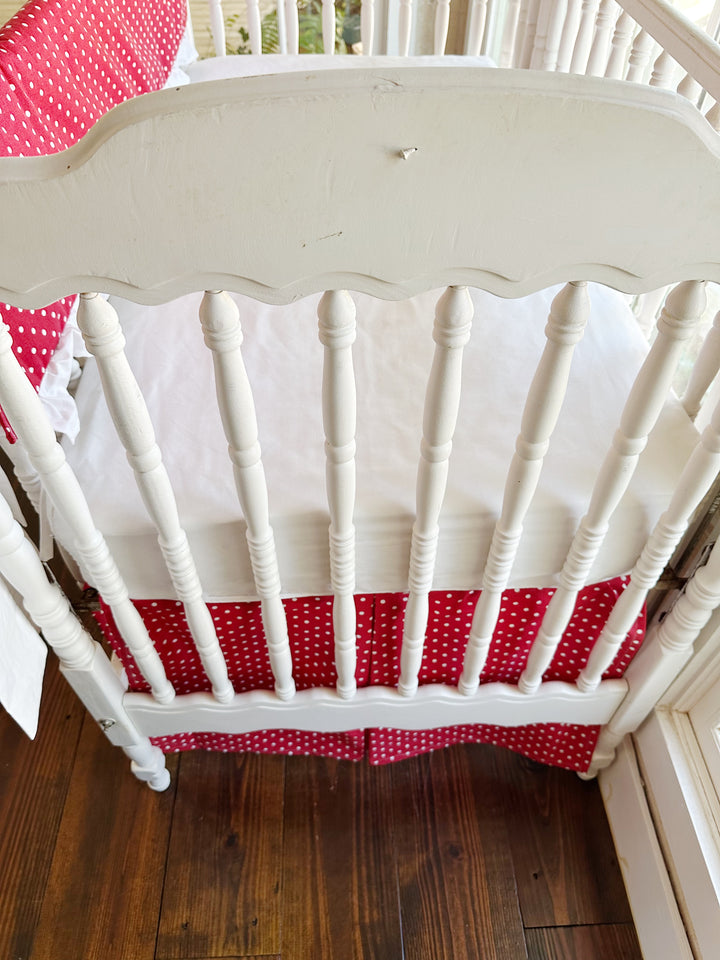 The scalloped headboard and turned spindles above the pleated red polka dot skirt