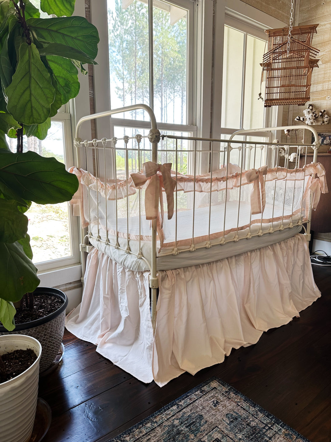 Close-up of white breathable mesh crib liner with ruffle trim and tie closures, farmhouse style