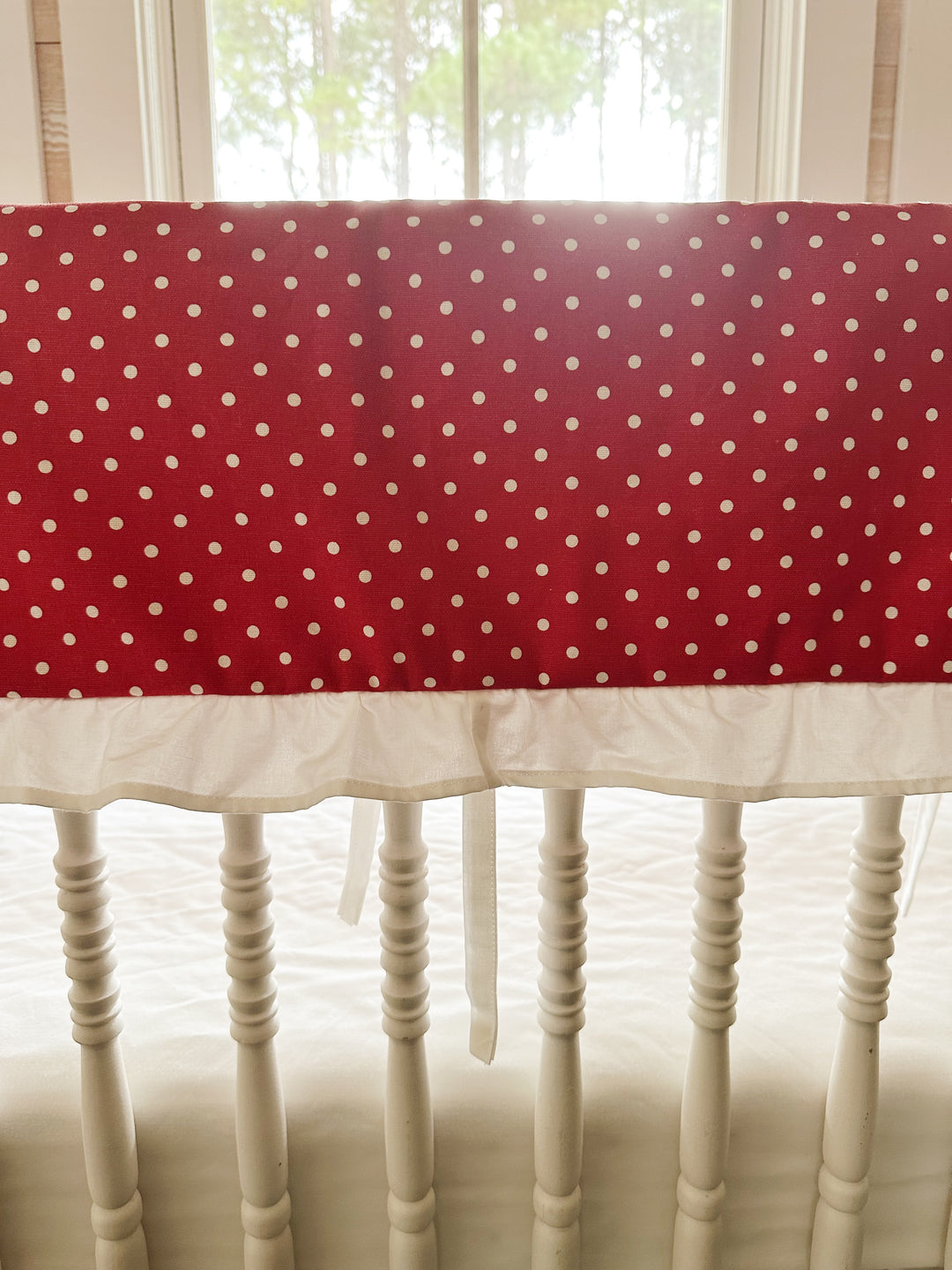Close view of the small white dots on deep cherry red cotton above the gathered white ruffle
