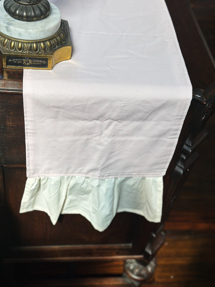 Plain end of the baby pink dresser runner hanging over a carved dresser corner, finished with a gathered ivory ruffle
