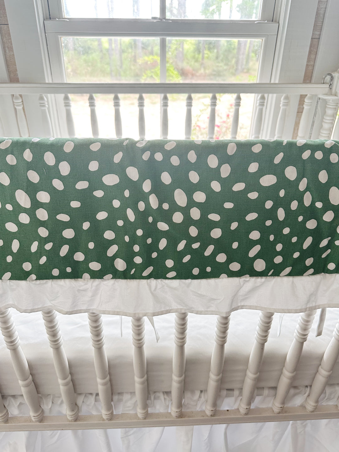 Close view of the irregular white spots on deep green cotton above the gathered white ruffle