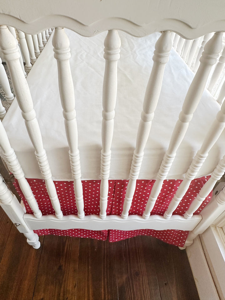 The split corner of the skirt where it wraps the crib leg, dots running to the hem