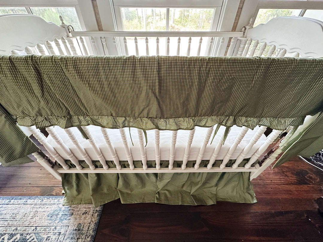 Overhead view of green gingham crib rail cover showing ruffle and inside detail
