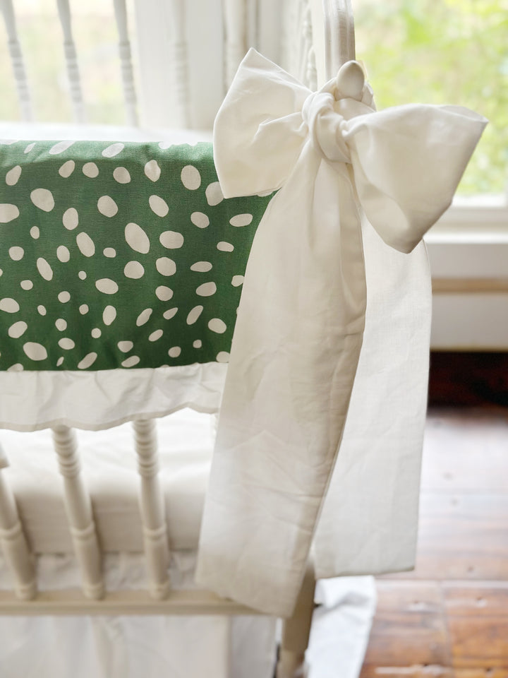 White sash knotted at the corner post beside the green dot panel and its white ruffle