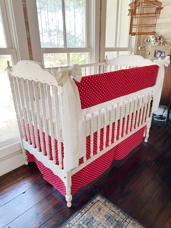 Angled view of the polka dot rail cover and matching dotted skirt, white sash on the near post