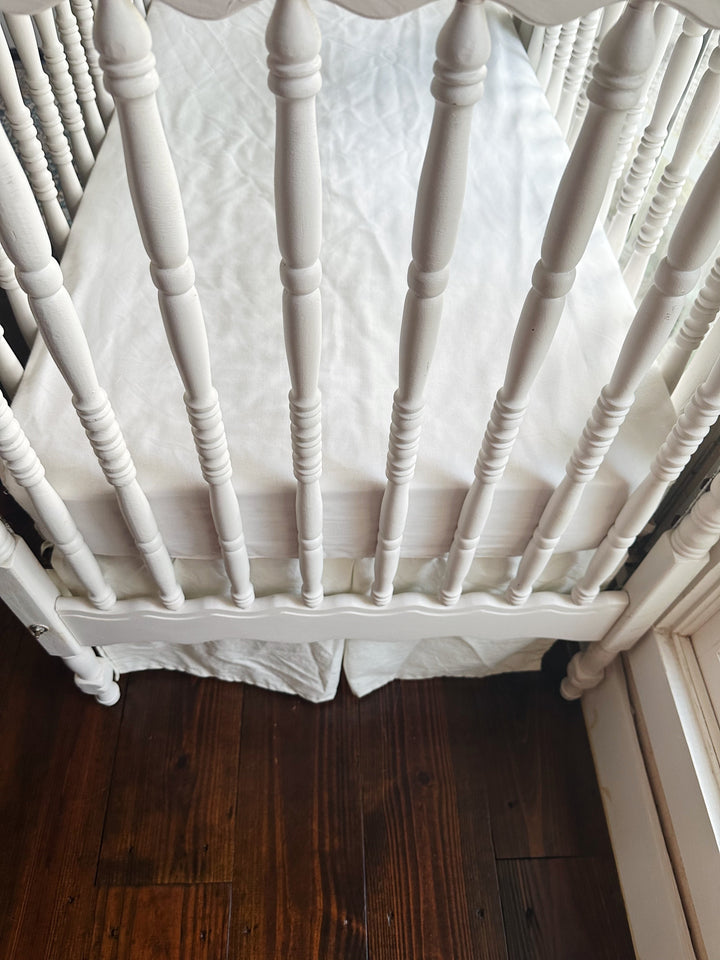 Foot of the crib showing the porcelain skirt hem falling to the floorboards - High Cotton Textile