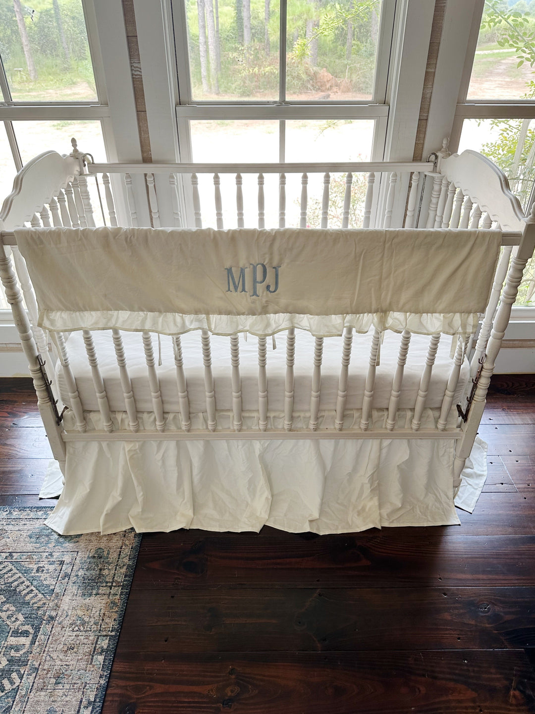 Looking down into the crib past the ruffled rail cover to the fitted sheet below