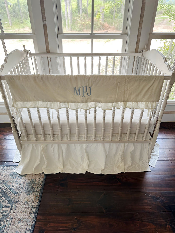 Looking down into the crib past the ruffled rail cover to the fitted sheet below