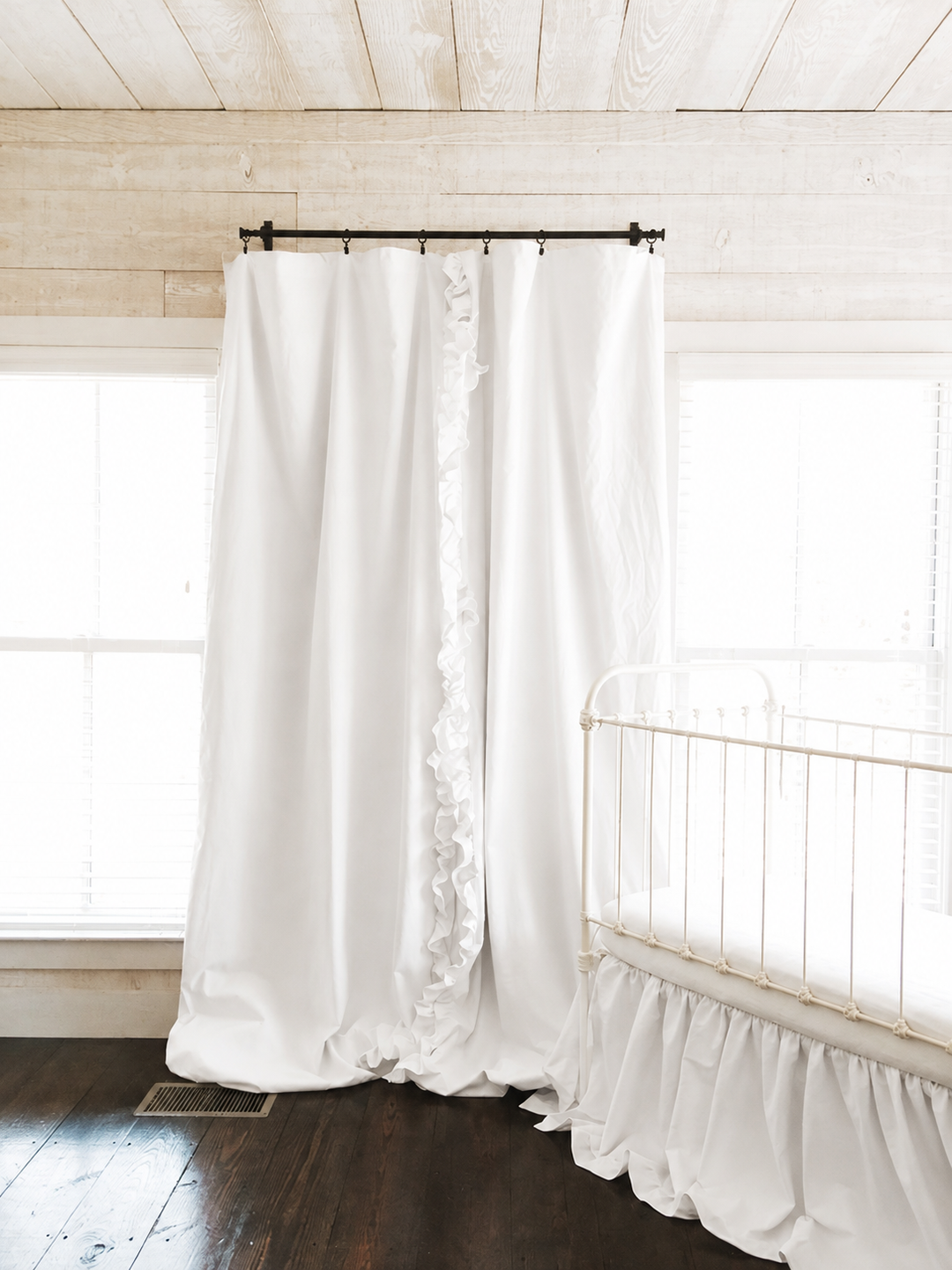 Full length white blackout curtains from rod to floor in a shiplap nursery with a white iron crib - High Cotton Textile