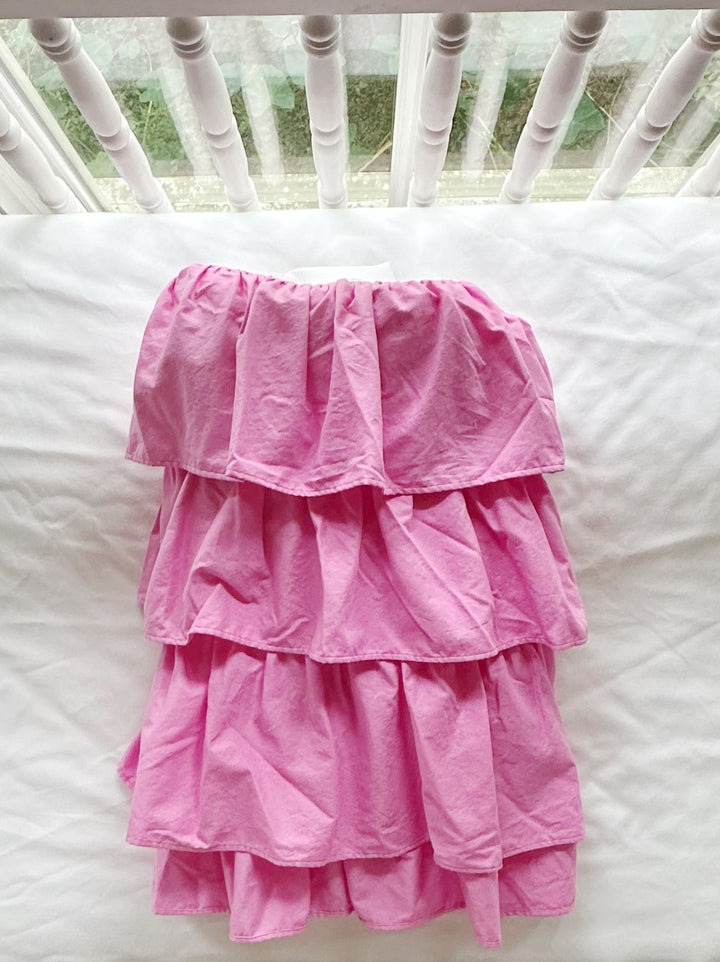 Parfait pink tiered crib skirt folded on a white crib mattress, showing the stacked gathered tiers