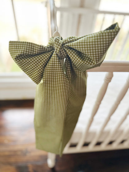 Green gingham crib bow with full loops and long tails against a sunlit window