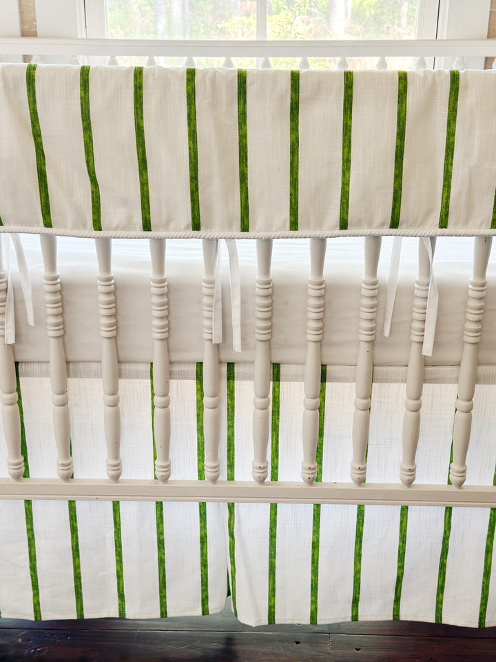 The rail cover's cording and white ties above the mattress, with the striped skirt below