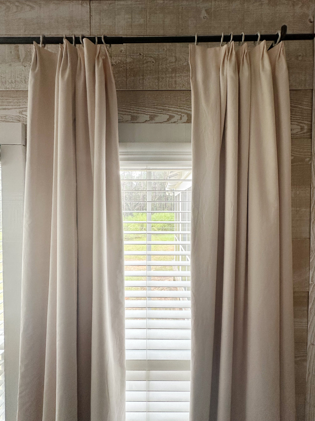 Upper half of the Ballet Slipper Pink euro pleat panels hung high on a black rod against whitewashed plank walls