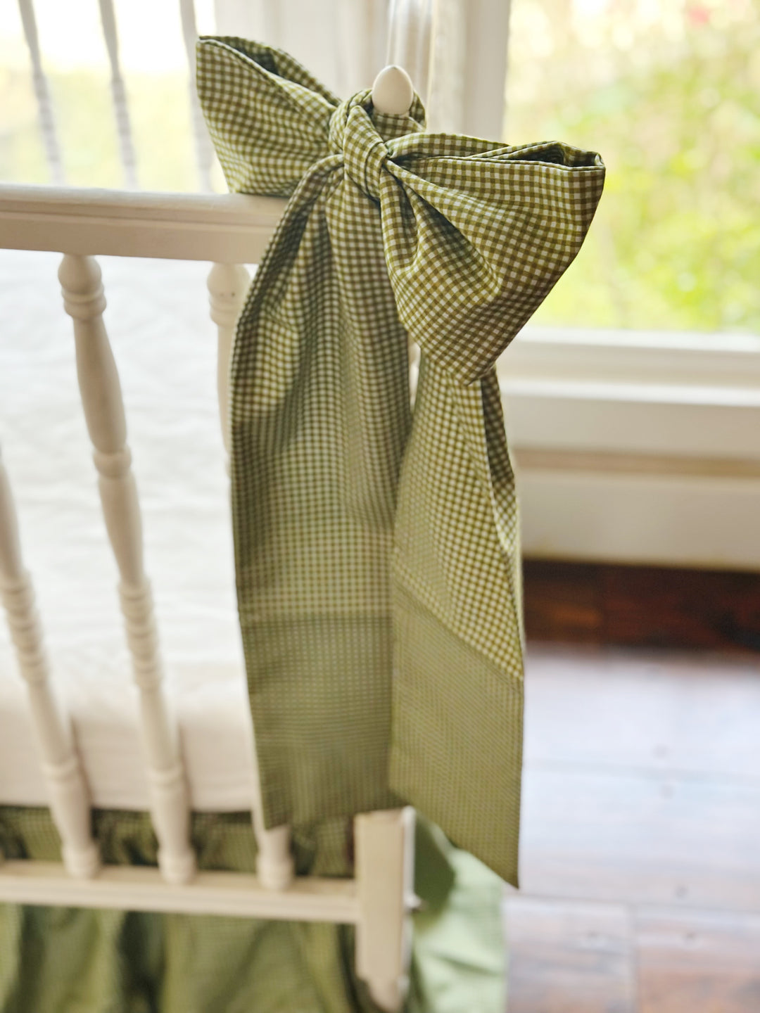 Large pine green gingham crib bow hand-tied to a white crib post