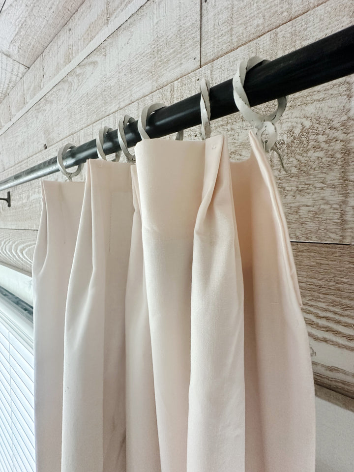 Angled view of the euro pleat header showing the pleated folds and white curtain rings on a black iron rod