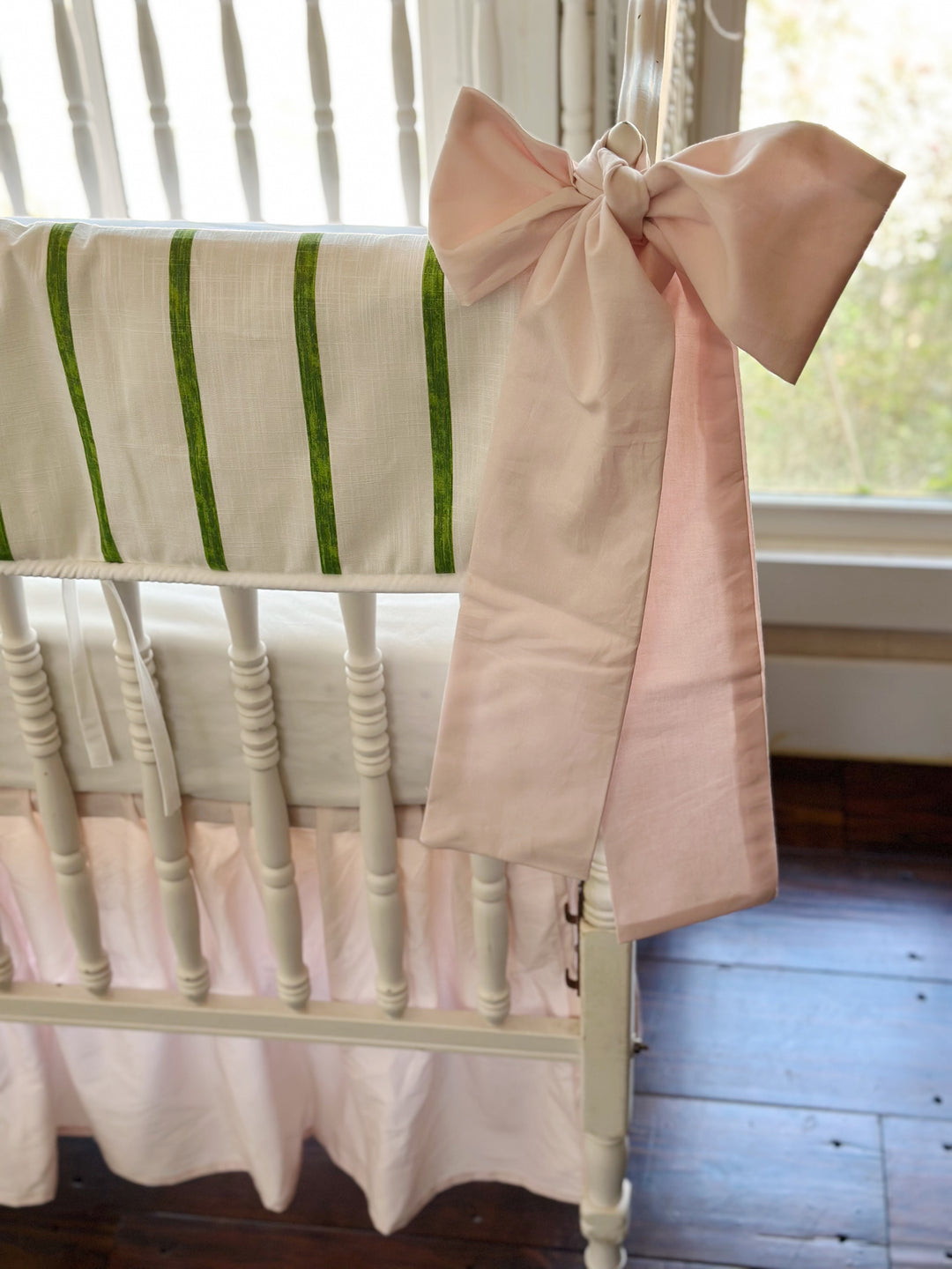 Close view of a baby pink sash knotted at the corner post beside the brushed green stripes