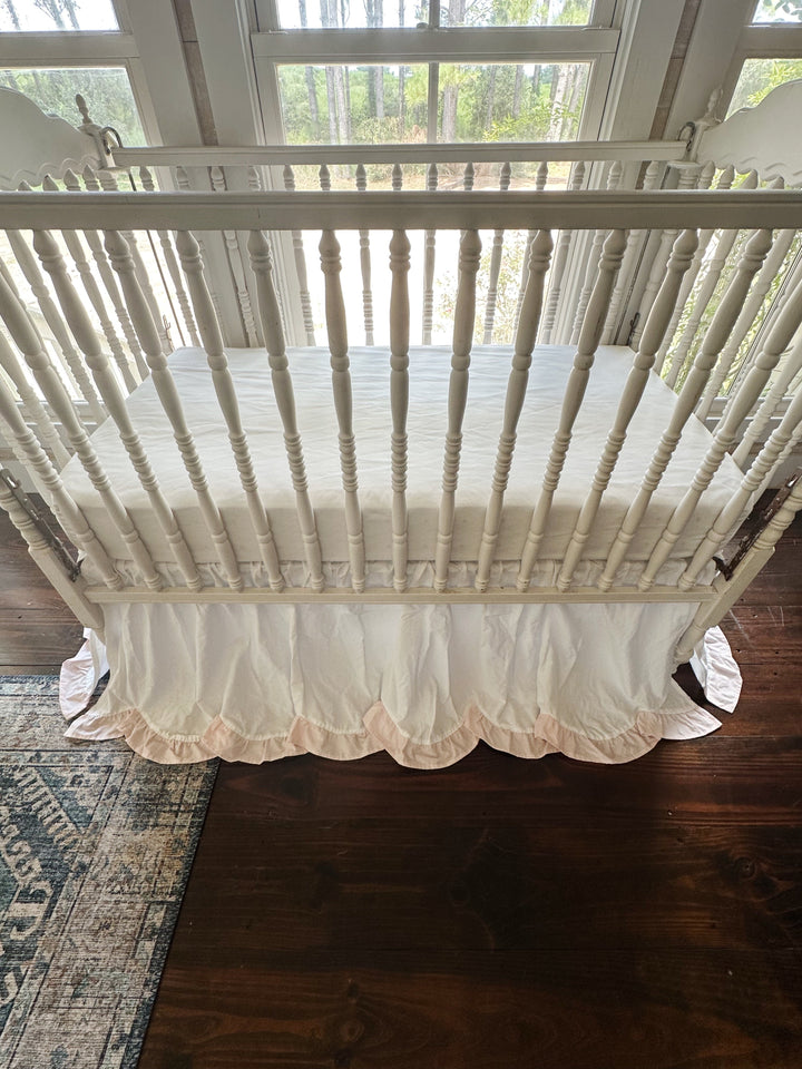 Front view of the crib with the scalloped skirt sweeping across the foot rail