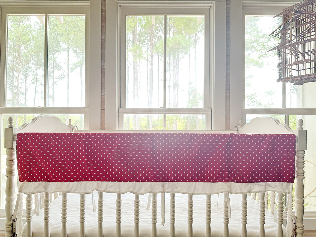 The polka dot rail cover seen straight on with its white ruffle and slim ties between the spindles