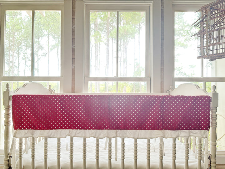 The polka dot rail cover seen straight on with its white ruffle and slim ties between the spindles