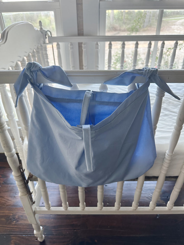 Baby blue crib caddy open at the top, showing the deep pouch and the center tie strap