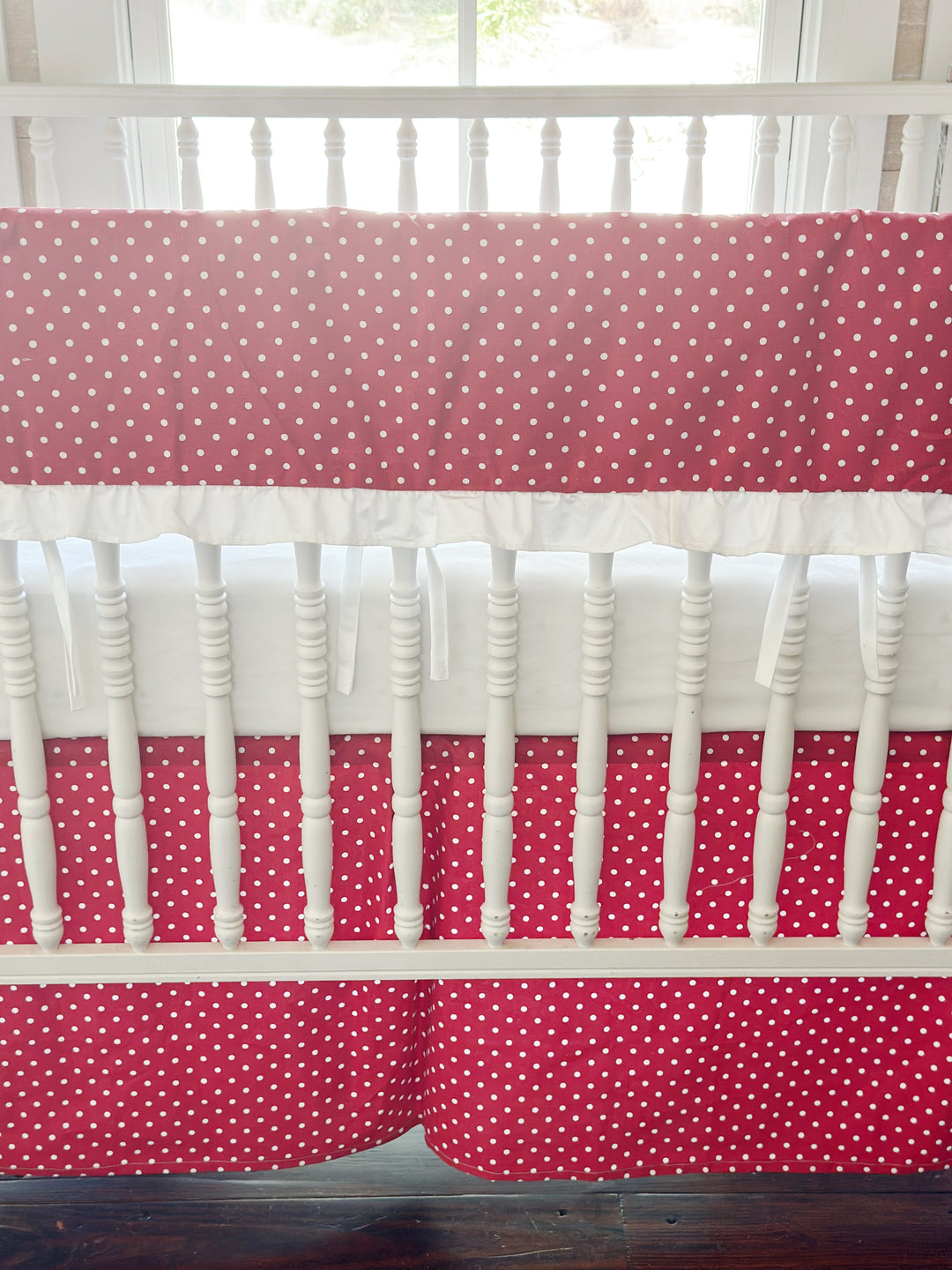 Close view of the small white dots on cherry red above the gathered white ruffle and slim white ties