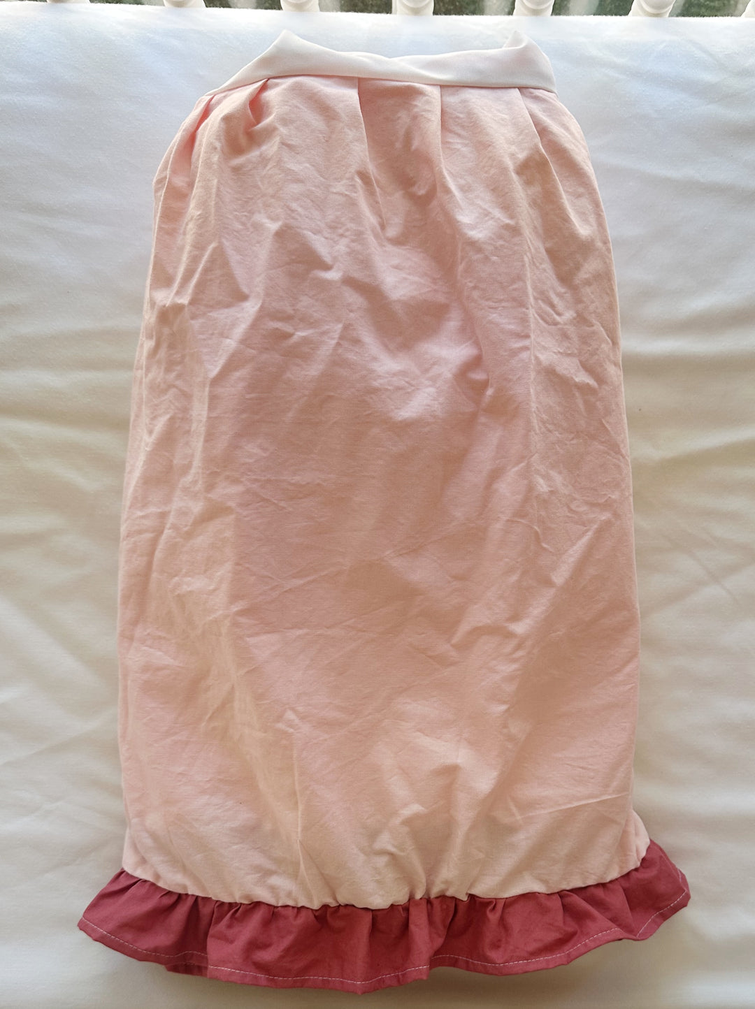 One side of the Sisters Pink & Blush crib skirt laid flat, gathered pink panel with the darker blush ruffle along the hem