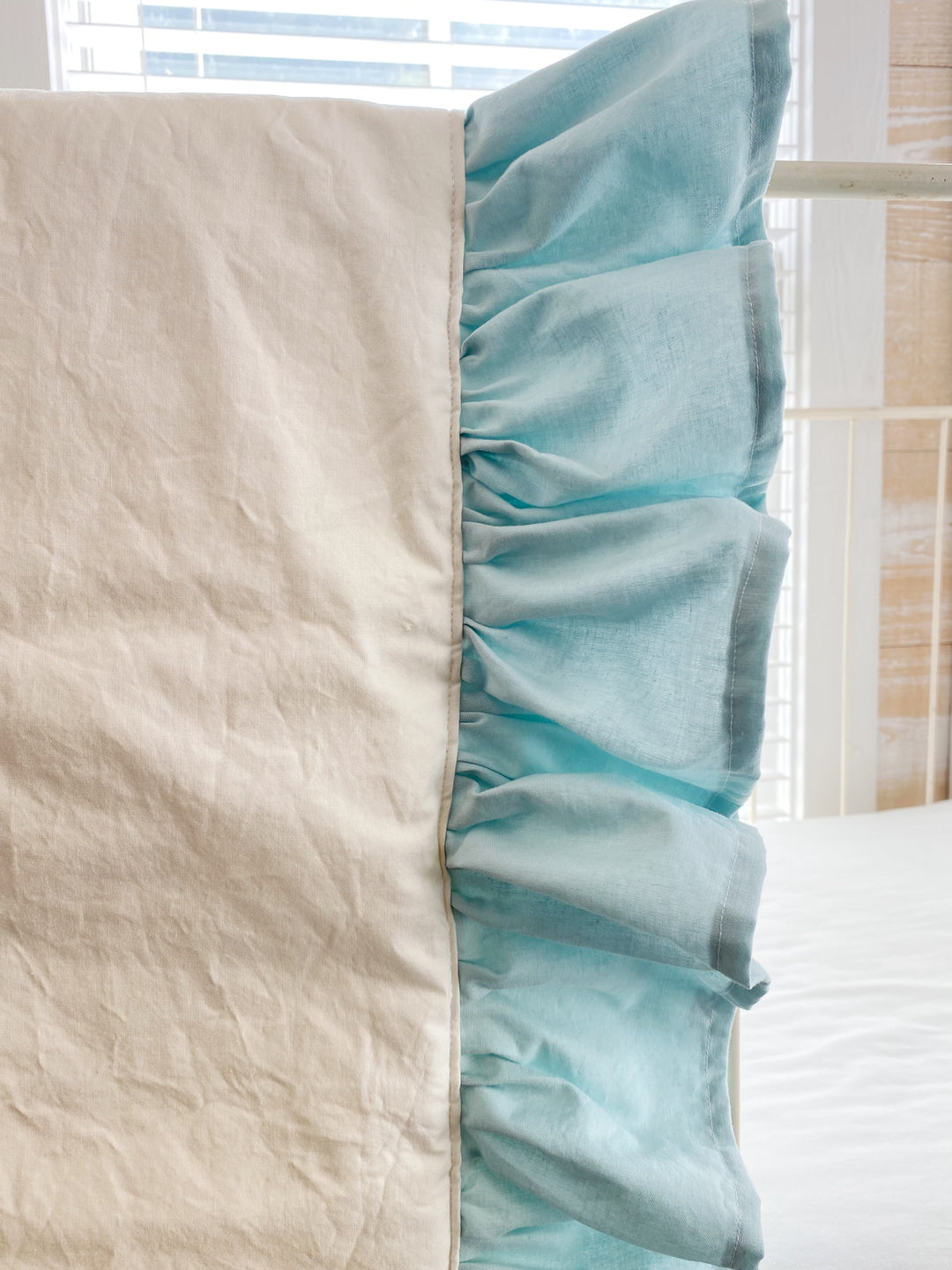 Close-up of the seam where the ivory quilt panel meets the gathered mist ruffle