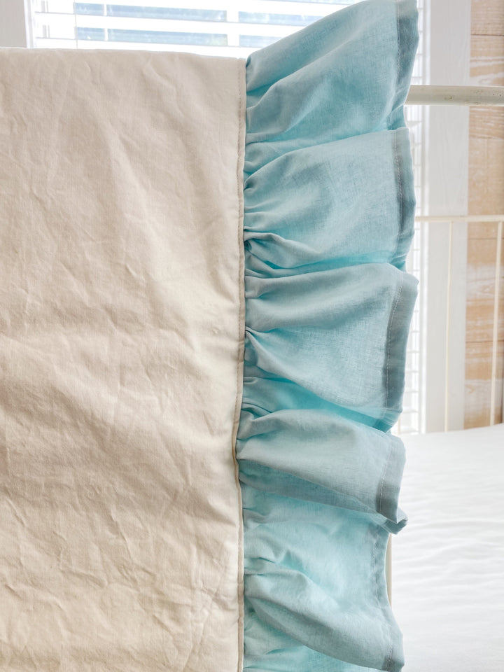 Close-up of the seam where the ivory quilt panel meets the gathered mist ruffle
